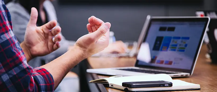 A photo of an employee sitting at a laptop and speaking and making motions with their hands. 