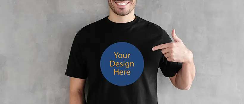 An individual wearing a black shirt and pointing to a decal that reads 'Your design here'. 