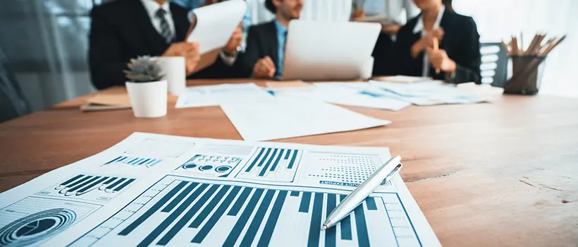 A pen atop a sheet of paper with graphs sitting on a conference table.