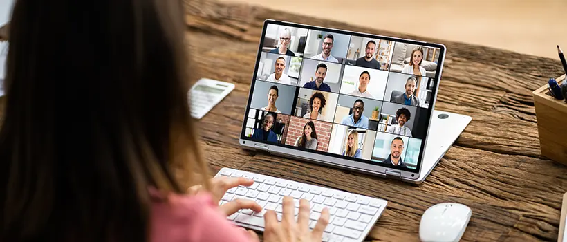 An employee on their laptop in a virtual meeting with coworkers.