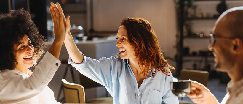 Employees at a cafe celebrating an achievement by slapping each other five.