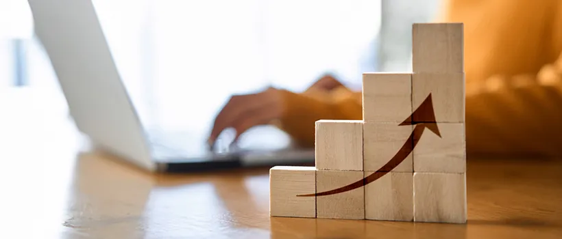 Wooden building blocks on a table with an illustration of an arrow pointing up. 